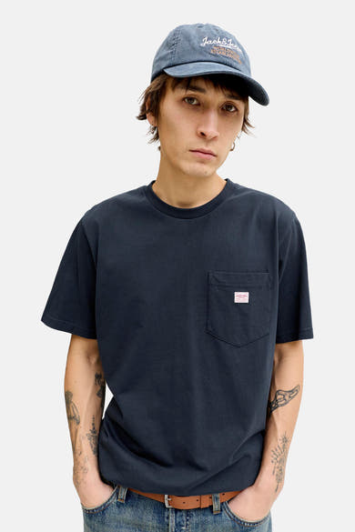 Blauw T-shirt met korte mouwen van PREMIUM BLUE by JACK & JONES, met borstzak, gedragen met een spijkerbroek en een pet.