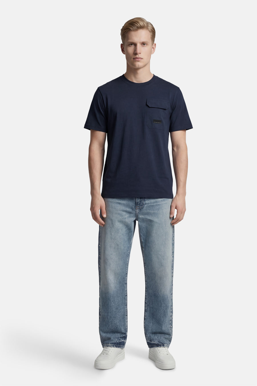 T-shirt à manches courtes bleu marine de JACK & JONES, avec poche poitrine et porté avec un jean bleu délavé.
