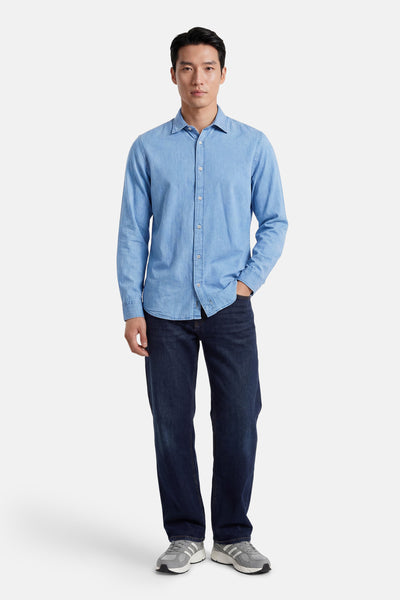 Blauwe spijkerblouse met lange mouwen en kraag van PREMIUM by JACK & JONES, gedragen met een donkere spijkerbroek en grijze sneakers.