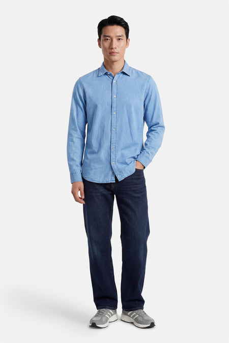 Chemise en jean bleue de PREMIUM by JACK & JONES à manches longues et col, portée avec un jean foncé et des baskets grises.