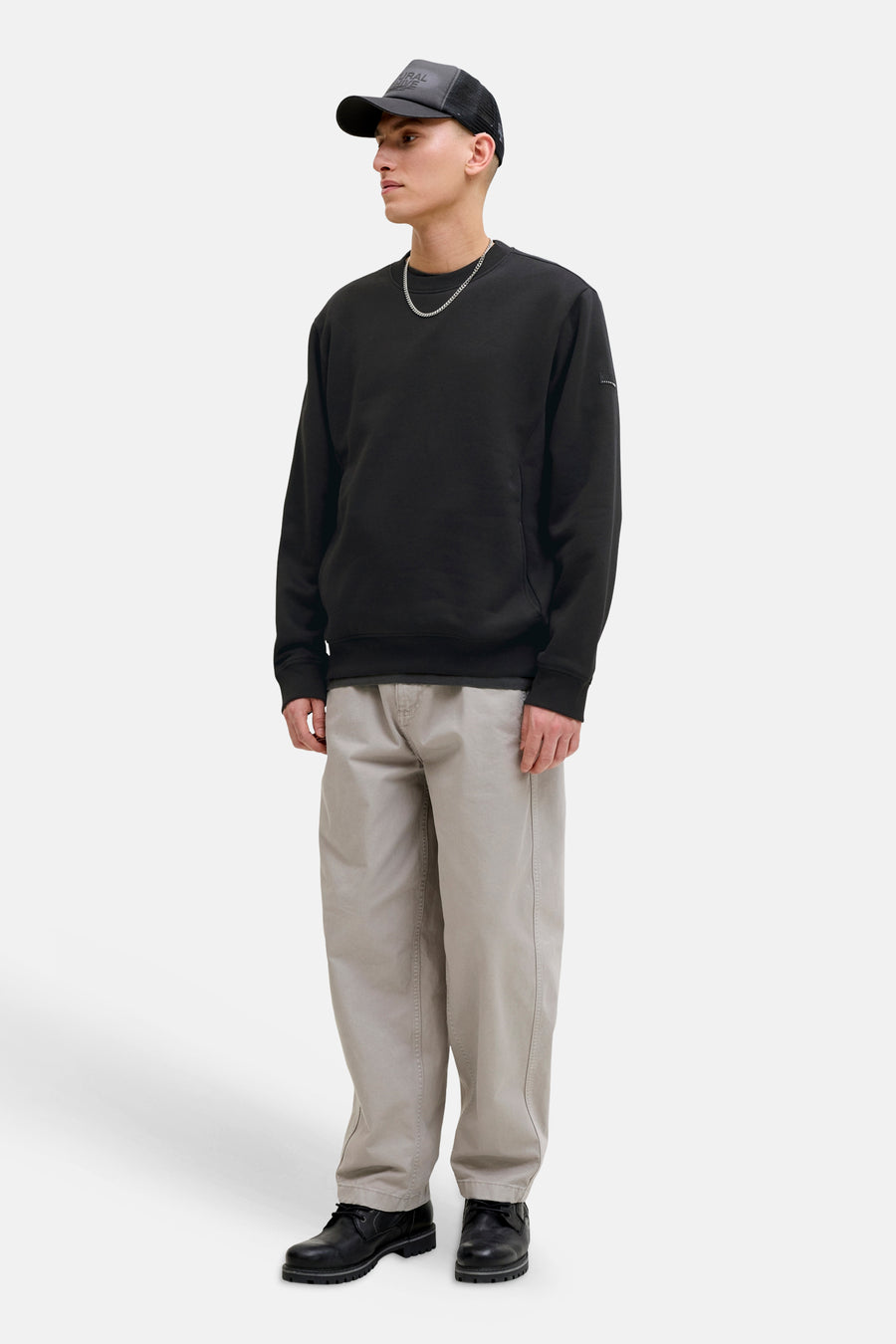 Zwarte rondehals sweatshirt van JACK & JONES, gedragen met een beige broek en zwarte schoenen.
