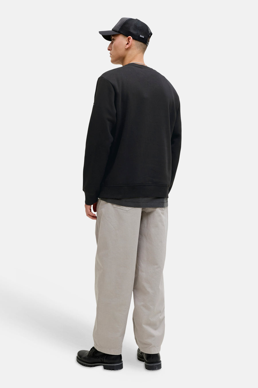 Zwarte rondehals sweatshirt van JACK & JONES, gedragen met een wijde beige broek en zwarte schoenen.