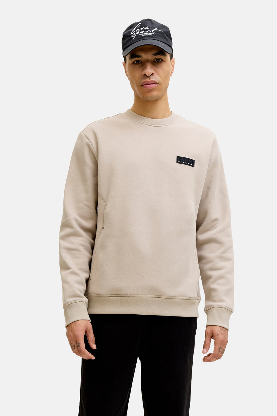 Beige rondehals sweatshirt van JACK & JONES, met een zwart embleem op de borst.