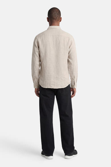 Chemise écru de PREMIUM by JACK & JONES en lin, à manches longues, vue de dos, portée avec un pantalon noir et des baskets.