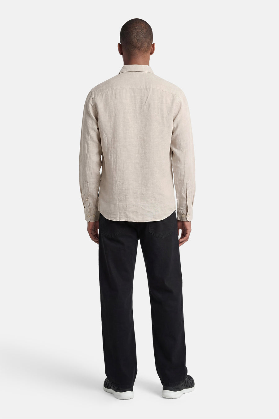 Chemise écru de PREMIUM by JACK & JONES en lin, à manches longues, vue de dos, portée avec un pantalon noir et des baskets.