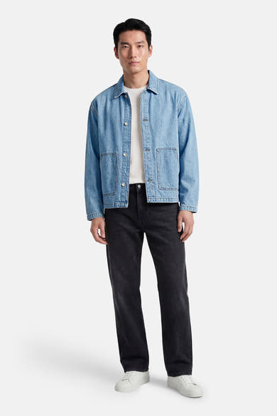 Veste en jean bleu clair en denim par ORIGINALS BY JACK & JONES, portée avec un t-shirt blanc et un pantalon noir.