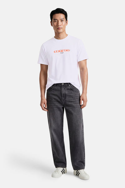 White short-sleeve t-shirt with orange chain graphic by MUNI, worn with dark jeans and white sneakers, front view.