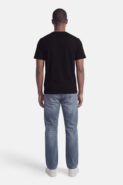 Black short-sleeve t-shirt back view on model with light blue jeans and white sneakers