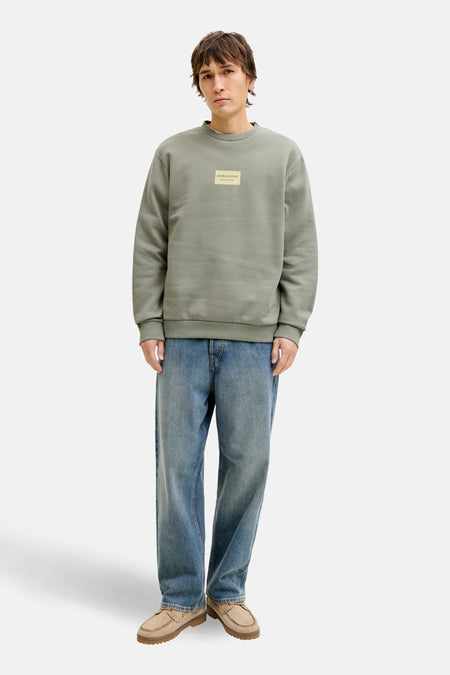 Sweat-shirt vert col rond de JACK & JONES, porté avec un jean bleu et des mocassins beiges.