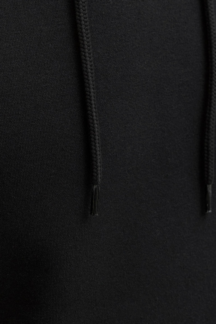 Black hooded sweatshirt with textured knit fabric and braided drawstrings, close-up front view
