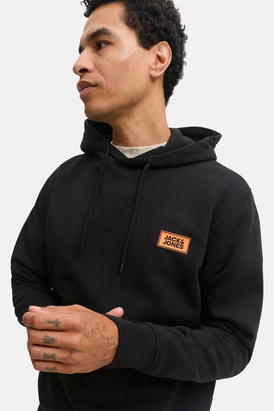 Black hoodie by Jack & Jones with orange logo patch, ribbed cuffs, and drawstring hood, shown in side view on model.
