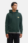 Dark green hooded sweatshirt by Jack & Jones with front logo patch, ribbed cuffs and hem, shown on model in front view.