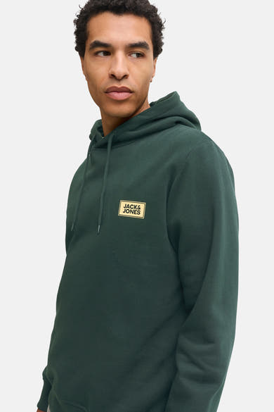 Dark green hooded sweatshirt by Jack & Jones with gold logo patch, side view on model