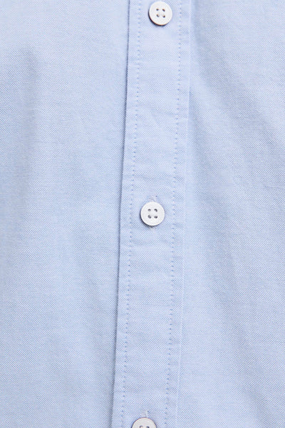 Light blue long-sleeve shirt with white buttons and fine textured fabric, close-up front view