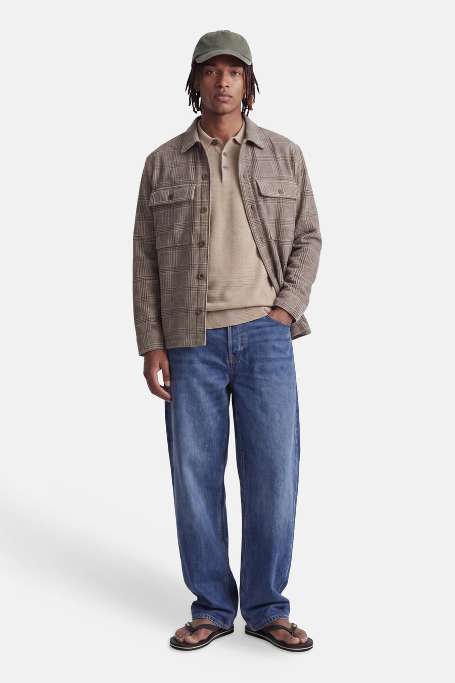 Beige ribbed turtleneck sweater with plaid overshirt, blue jeans, and flip-flops, front view.
