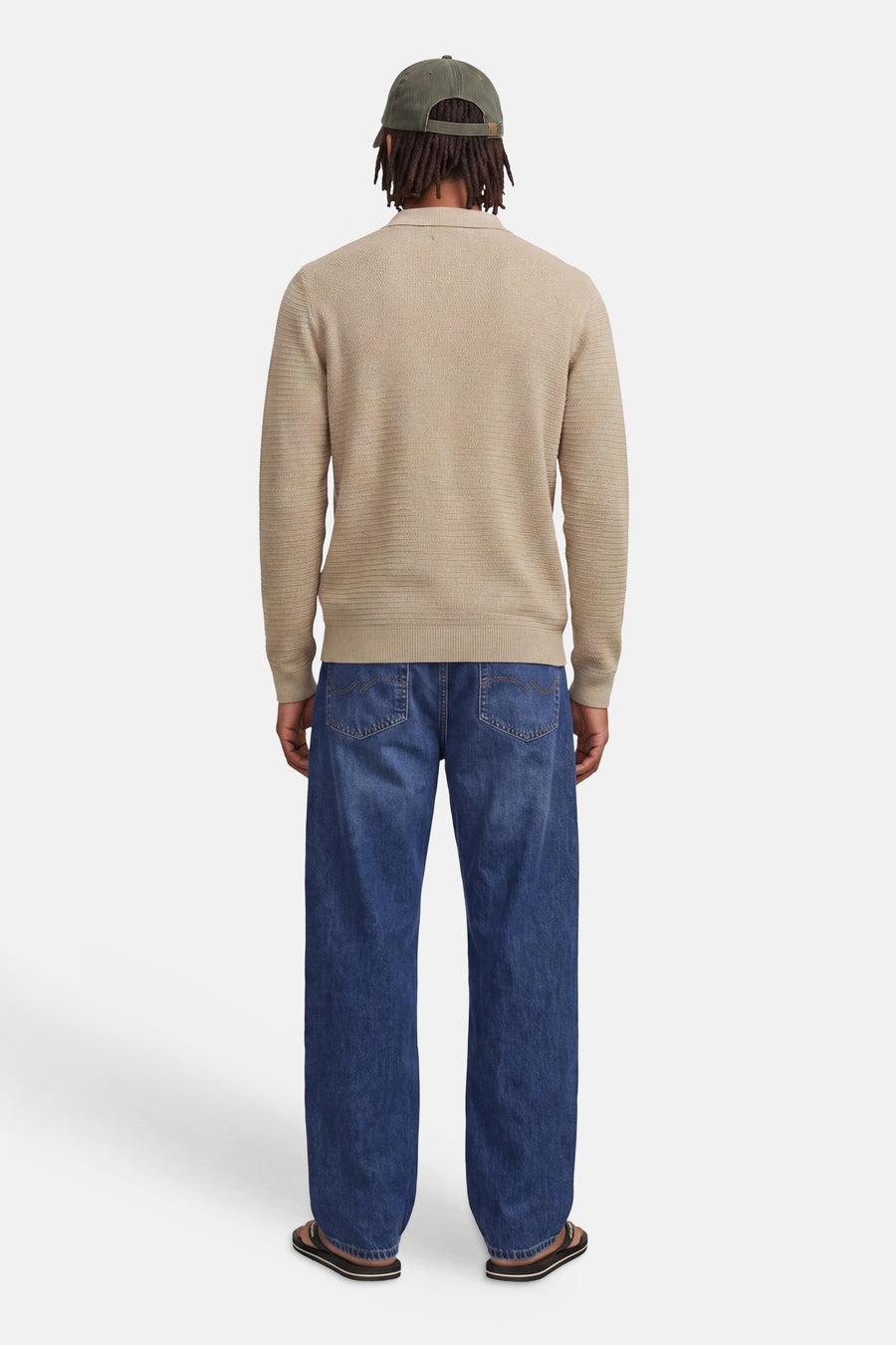 Beige ribbed knit turtleneck sweater back view with long sleeves, worn with blue jeans and olive cap