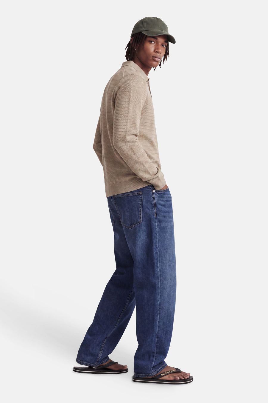 Beige ribbed knit turtleneck sweater by Jack & Jones, side view on model wearing blue jeans and black flip-flops.