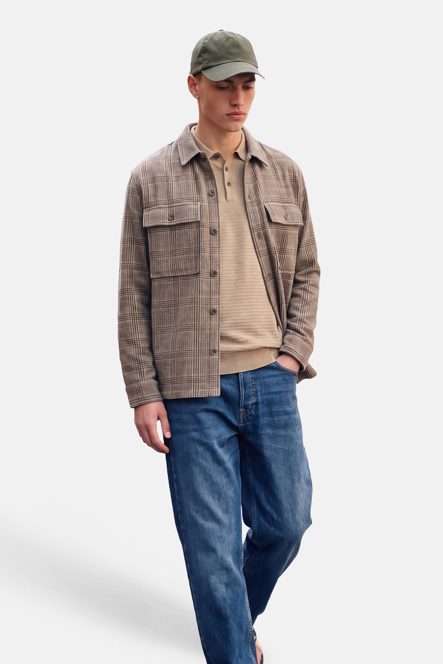 Yellow turtleneck sweater worn under plaid shirt with front pockets, paired with blue jeans and olive cap, full-body lifestyle view