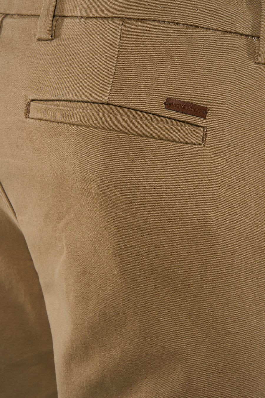 Zoom sur la poche arrière d’un chino beige JACK & JONES avec étiquette en cuir marron.