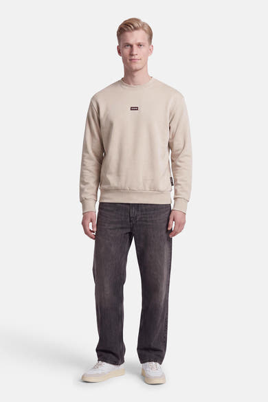 Sweat col rond écru JACK & JONES porté par un mannequin, avec petit logo sur la poitrine.