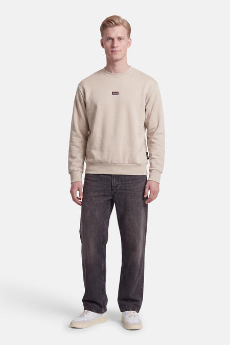 Sweat col rond écru JACK & JONES porté par un mannequin, avec petit logo sur la poitrine.