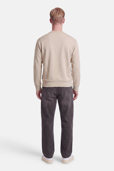 Vue de dos d’un mannequin portant un sweat col rond écru JACK & JONES et un jean gris.