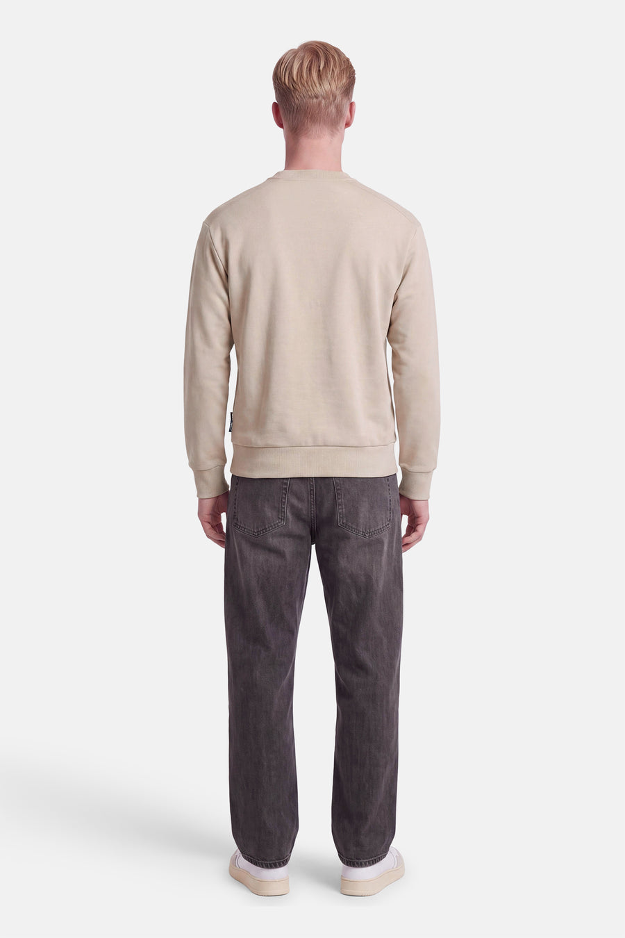 Vue de dos d’un mannequin portant un sweat col rond écru JACK & JONES et un jean gris.