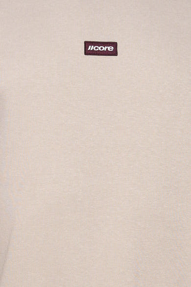Détail du sweat col rond écru JACK & JONES avec écusson « JCORE ».