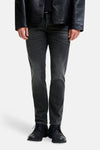 Black slim-fit denim jeans by Glenn, featuring a dark wash with subtle fading, shown on model with black leather jacket and lace-up shoes, front view.