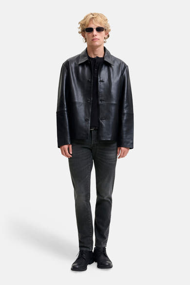 Black slim-fit denim jeans by Glenn, featuring a dark wash with subtle fading, worn with a black leather jacket and boots in a full-length front view.