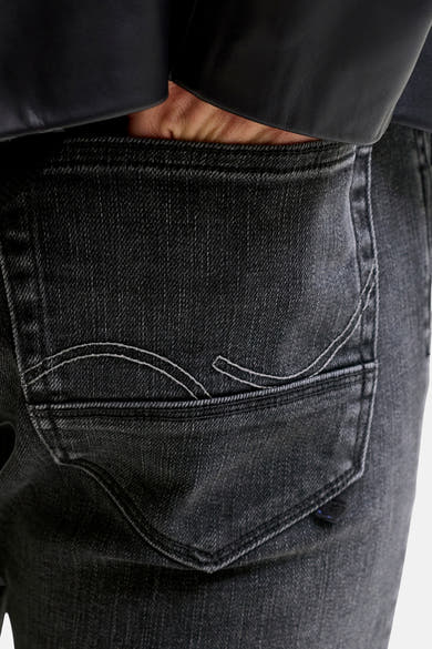 Black slim-fit denim jeans with faded texture and white contrast stitching on back pocket, shown in close-up view