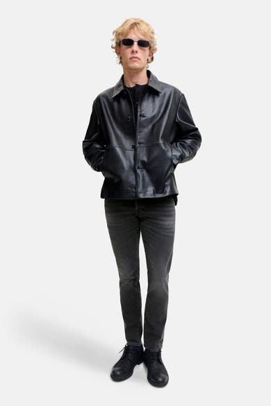 Black slim-fit denim jeans by GLENN, worn with a black leather jacket and boots, full-length front view on model