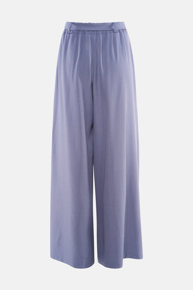 Pantalon costume bleu Terra di Siena, ample et fluide, avec une taille élastiquée, sur un fond neutre.
