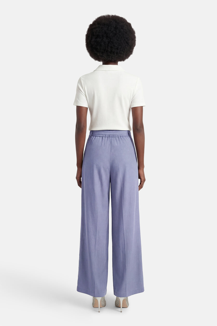 Terra di Siena blauwe pantalon, wijde pasvorm, gedragen met een witte polo en pailletten pumps, achtergezicht.