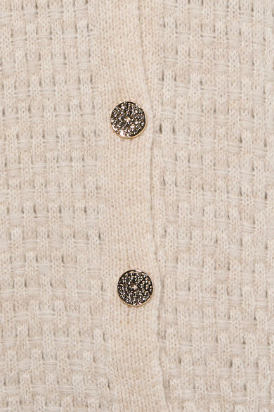 Gilet écru en tricot texturé par Terra di Siena, boutons dorés ornés de motifs délicats, vue rapprochée
