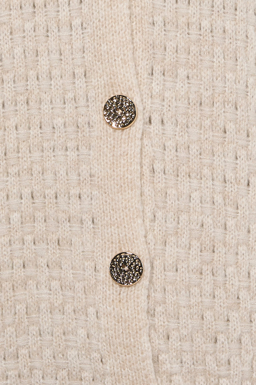 Gilet écru en tricot texturé par Terra di Siena, boutons dorés ornés de motifs délicats, vue rapprochée