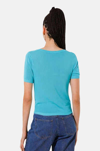 Pull à col rond turquoise de GOA GOA, coupe courte, porté avec un jean bleu pailleté.