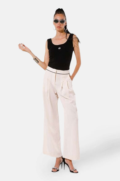Beige kostuumbroek van GOA GOA, wijd en hoge taille, gedragen met een zwarte tanktop en pumps.