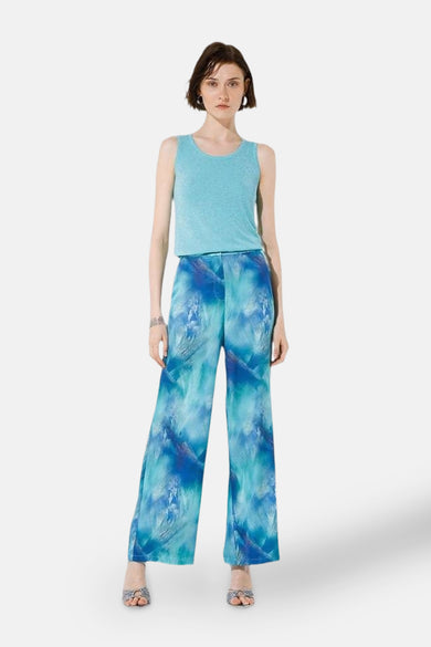 GOA GOA blauwe wijde broek met wervelend patroon, gedragen met een turquoise tanktop en sandalen met hak.