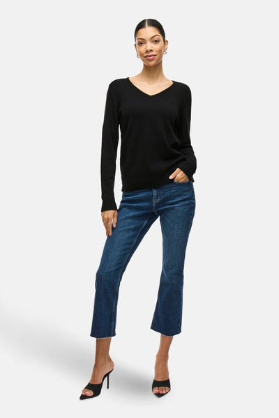 Pull noir de VILA, porté avec un jean évasé et des mules à talons aiguilles.