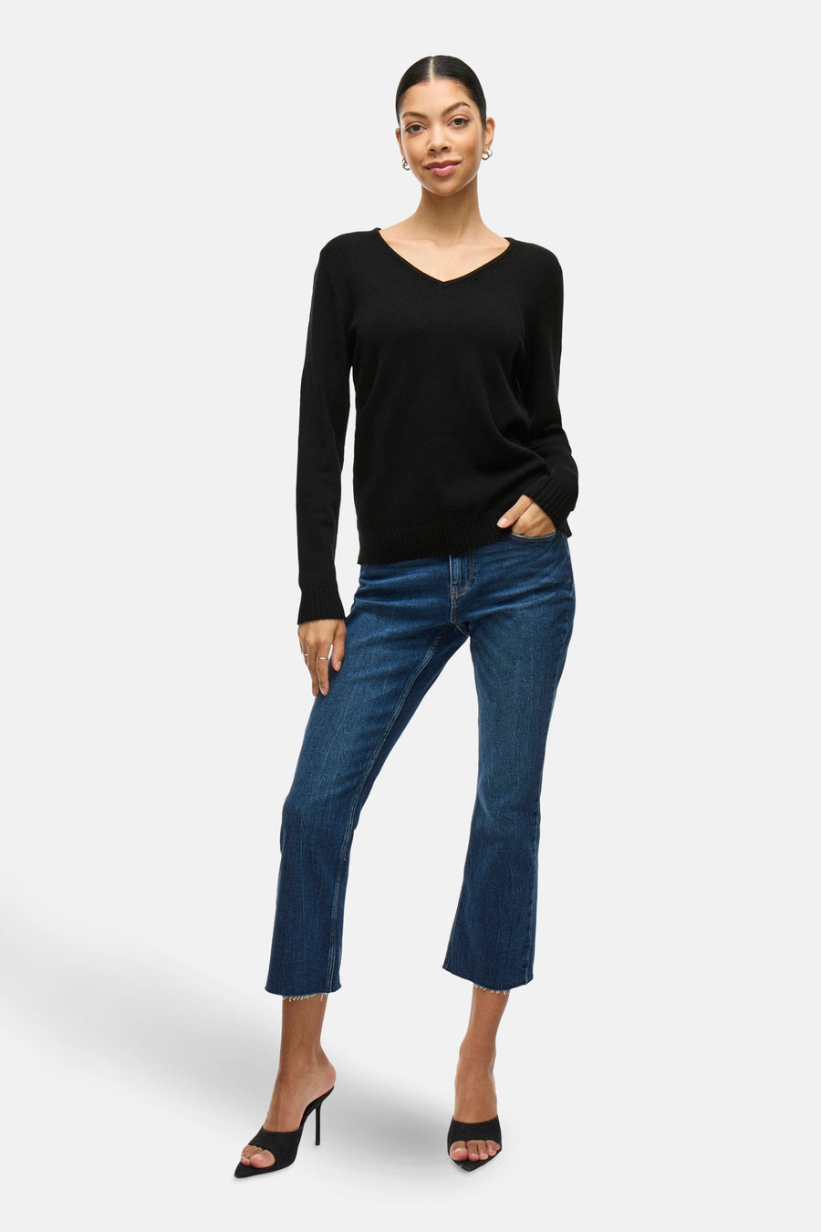 Pull noir de VILA, porté avec un jean évasé et des mules à talons aiguilles.