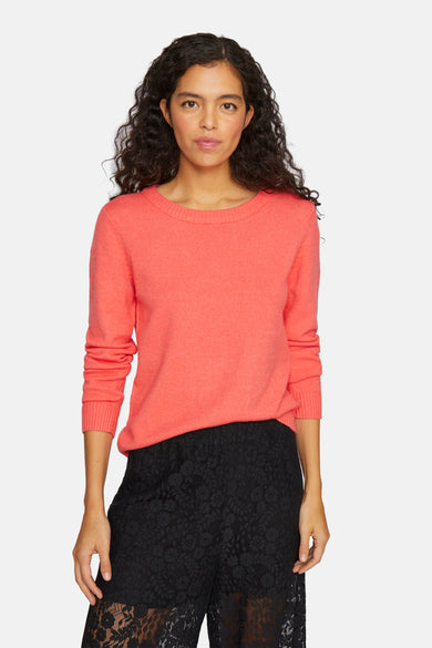 Pull corail à col rond de VILA, porté avec une jupe noire en dentelle.