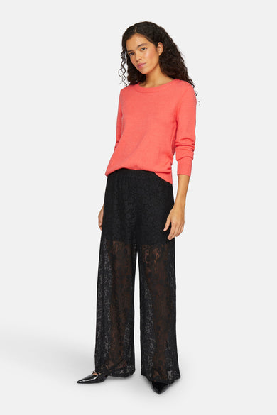 Pull à col rond corail de VILA®, porté avec un pantalon large en dentelle noire.