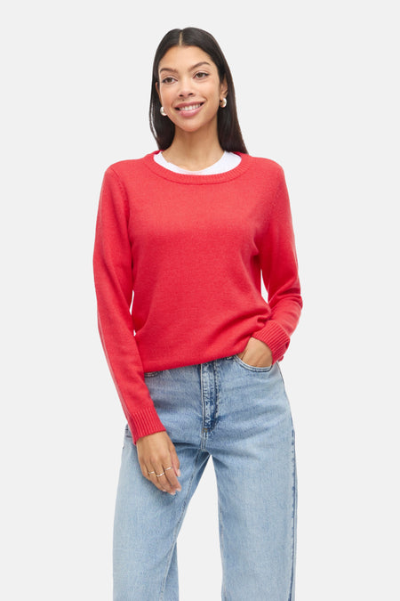 Pull à col rond rouge de VILA®, porté avec un t-shirt blanc et un jean bleu clair.