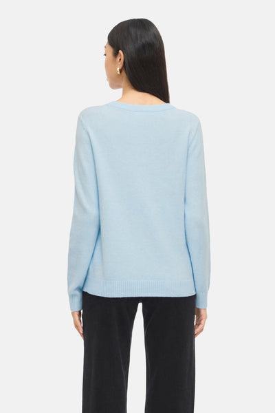 Pull bleu à col rond de VILA®, porté avec un pantalon noir taille haute, vue de dos.