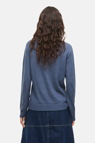 Ronde hals trui blauw van VILA®, gedragen met een donkerblauwe spijkerrok, achterzijde.