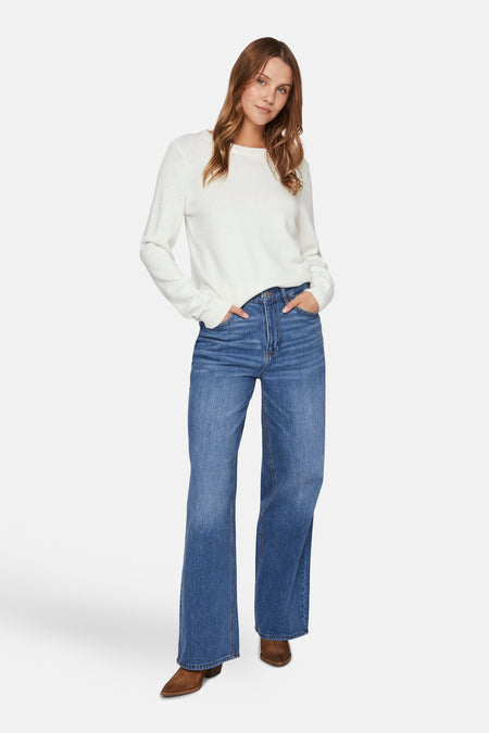Pull col rond blanc de VILA®, porté avec un jean taille haute et des bottines marron.