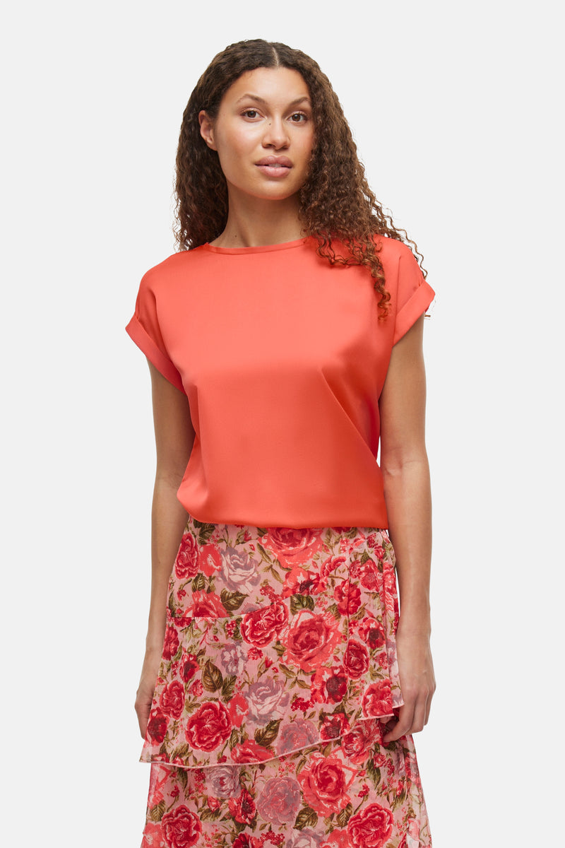 Koraalkleurig T-shirt met korte mouwen van VILA®, gedragen met een lange, bloemige rok met ruches.