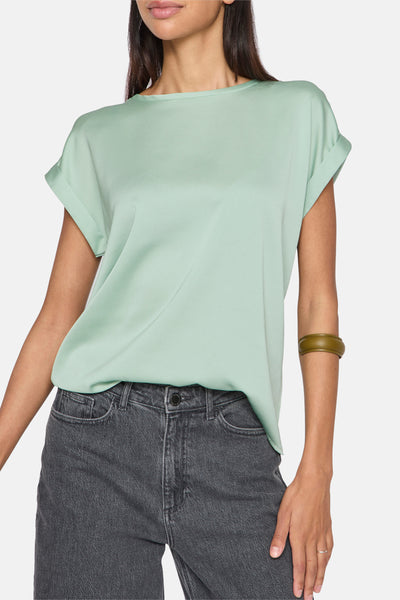 Groen T-shirt met korte mouwen van VILA®, gedragen met een grijze jeans en een groen armbandje.