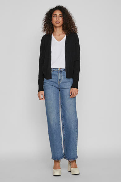 Gilet noir par VILA®, porté sur un t-shirt blanc et un jean bleu ample, complété par des chaussures à plateforme.
